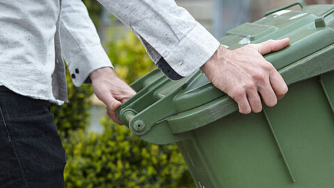 Persoon houdt groene kliko vast